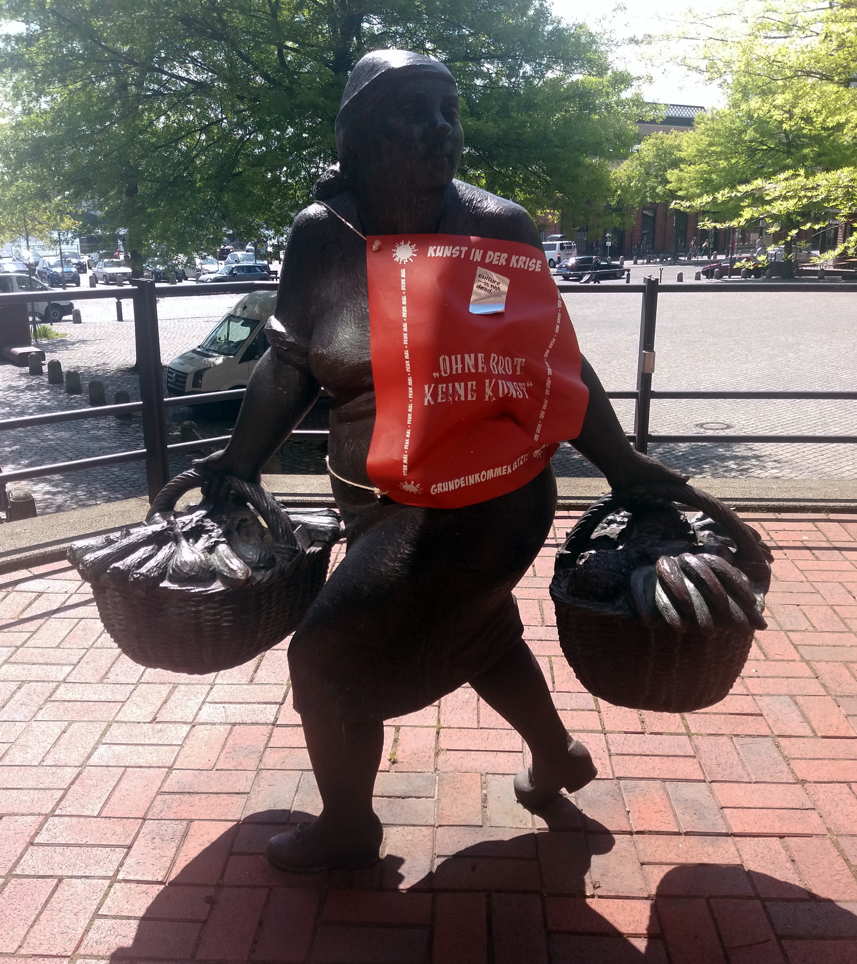 Figure 1: Sculpture of a vendor dressed in a poster saying 'Art in crisis' & 'No art without bread' by a basic income-initiative